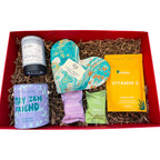 Gift set with various items including a mug, bath salts, and a plant kit in a red box.